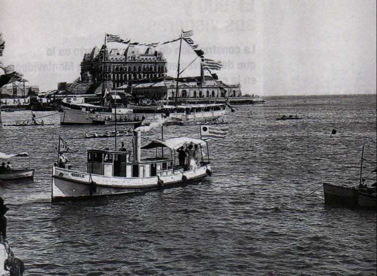 Races organized by the Montevideo Rowing Club in Montevideo Bay. The Hotel Nacional, in the background, was one of the greatest schemes of the National Company of Credit and Public Works. Victim of the 1890 crisis, the building  was never operational, and the French manager stayed some years in the empty hotel waiting for an inauguration that never happened.